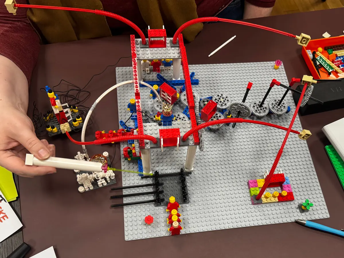 LEGO SERIOUS PLAY Modell mit Figuren, Zahnrädern und verbindenden Röhren auf dem Arbeitstisch